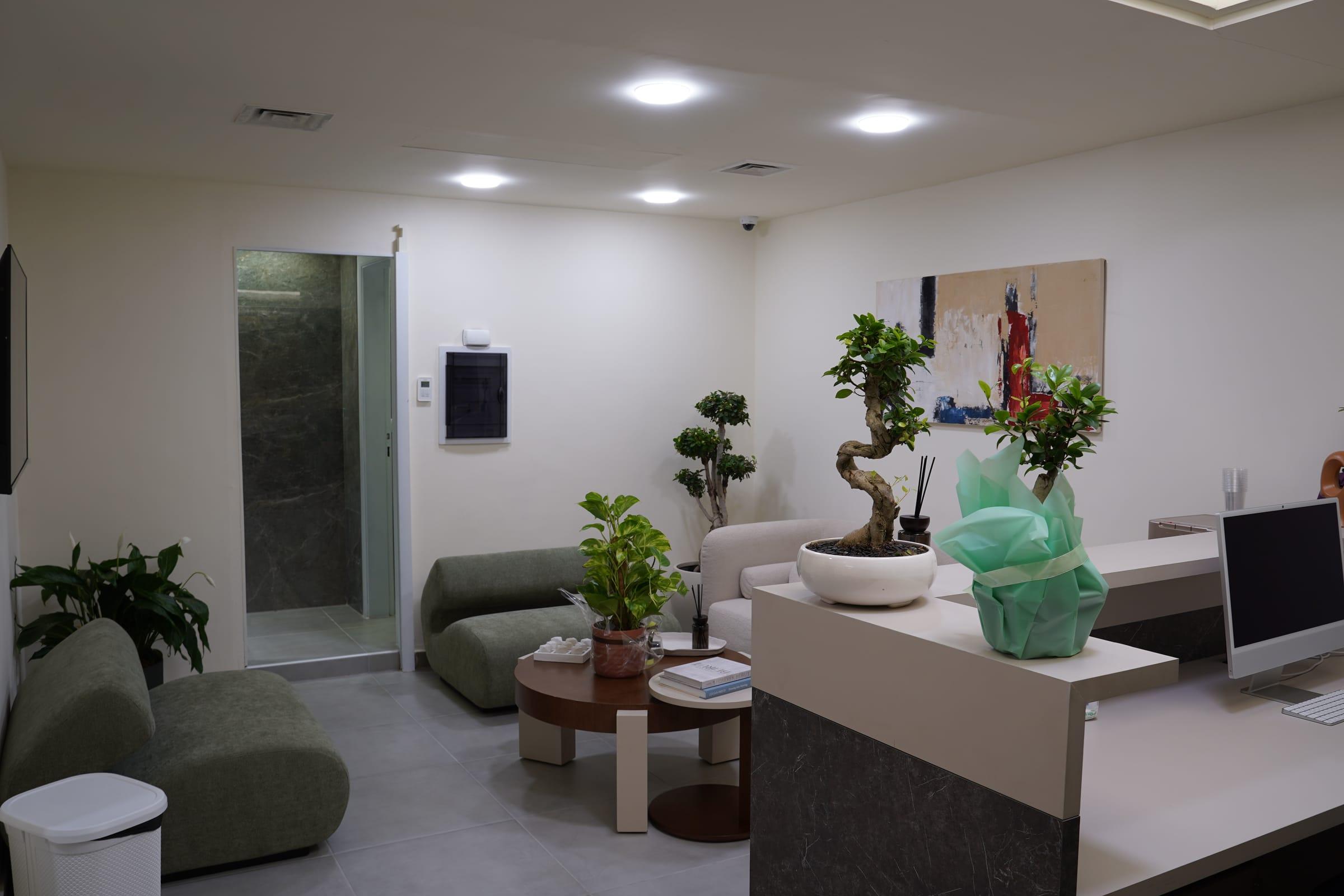 Reception desk and waiting area with seating and bonsai trees at the Le Dermato clinic