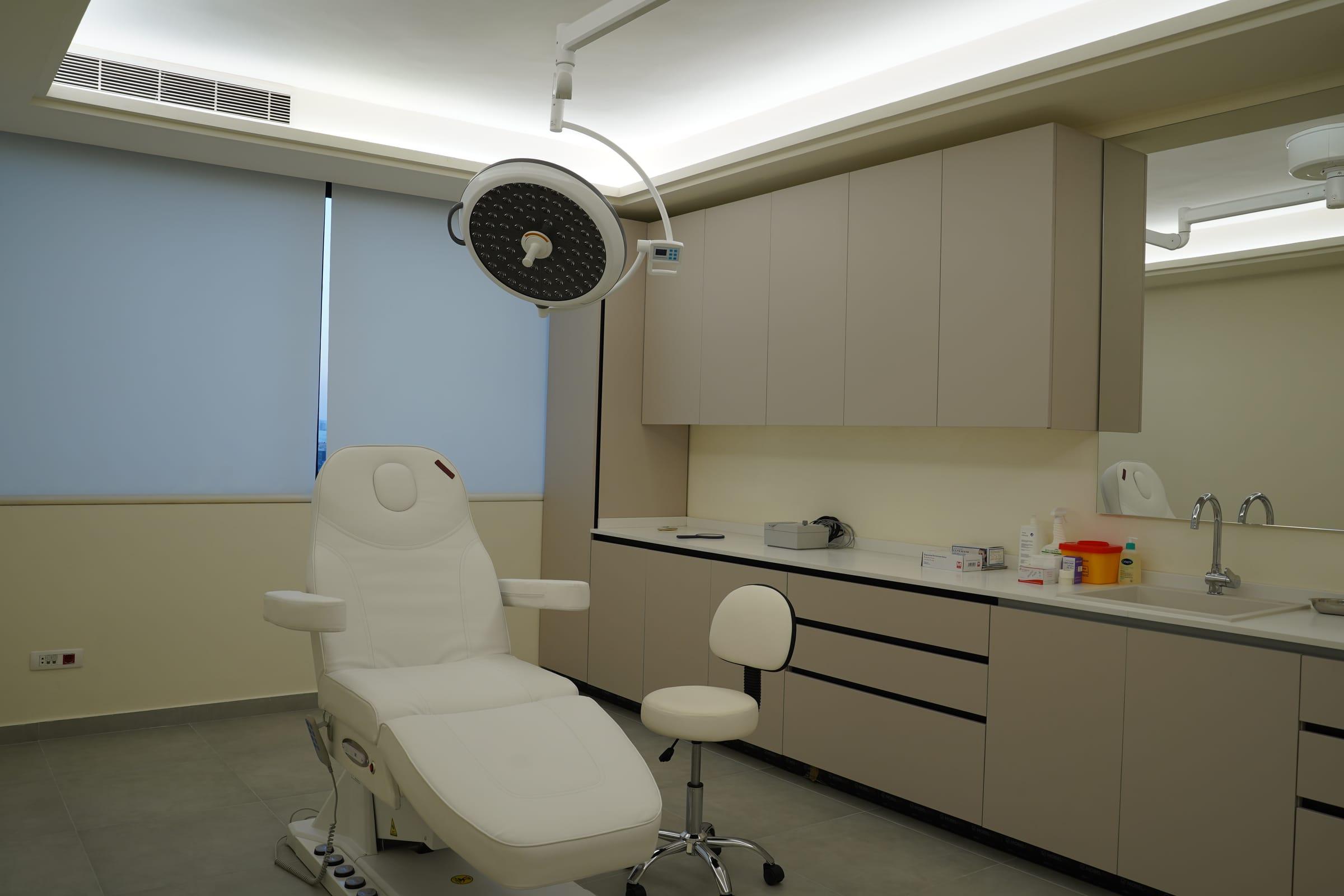 Treatment room with a reclining chair and cabinets at the Le Dermato clinic in Dbayeh