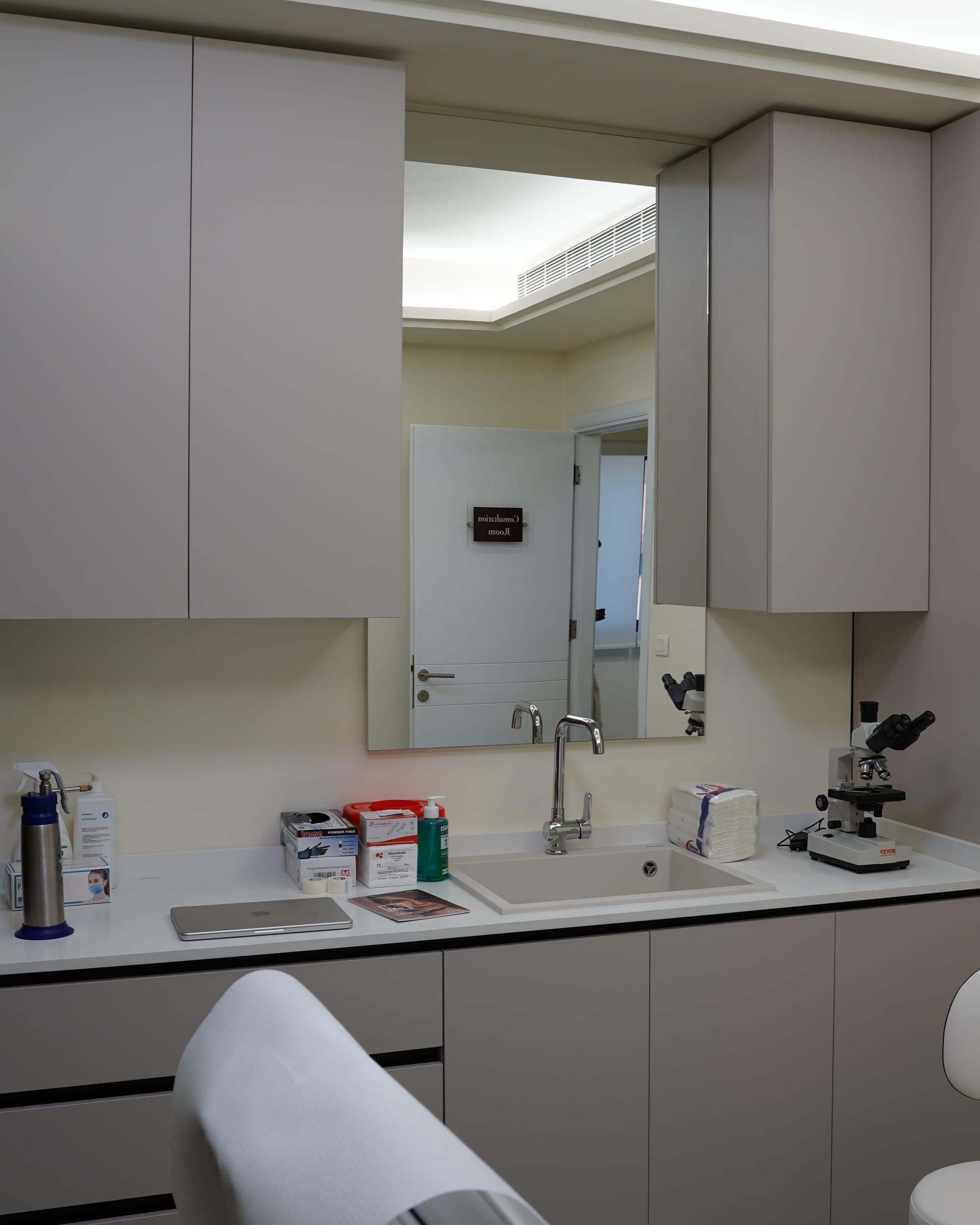 Procedure room with treatment couch, sink and cabinets at Le Dermato